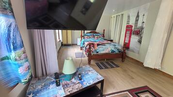 Un dormitorio con una cama, un escritorio, una lámpara y una pared con un mural de paisaje urbano.