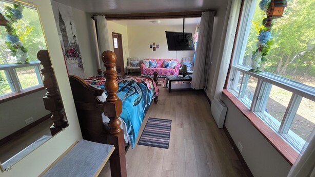Quarto com cama, sofá, televisão e janela com cortinas.