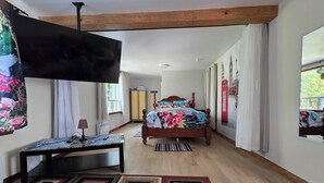 Quarto com cama, televisão, escrivaninha e guarda-roupa.