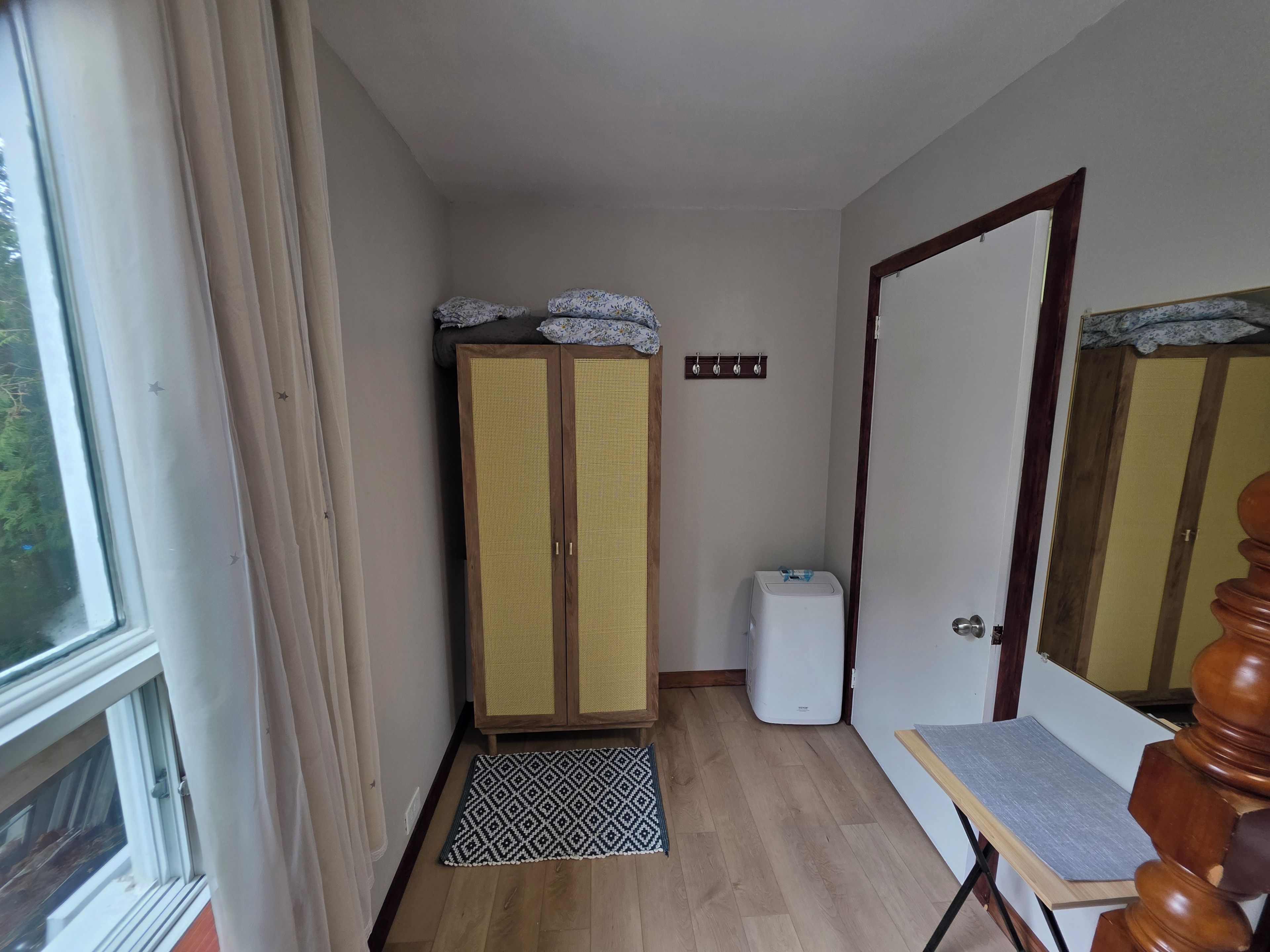 Un couloir avec un placard, une petite table et un appareil électroménager blanc.