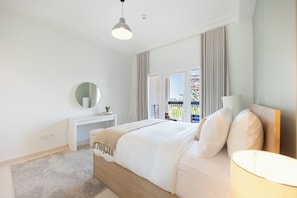 Habitación de hotel con cama, mesita de noche, espejo, lámpara y vistas al exterior.