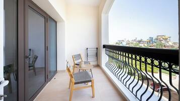 A balcony with a view of a cityscape, a sliding glass door, and a table with two chairs.