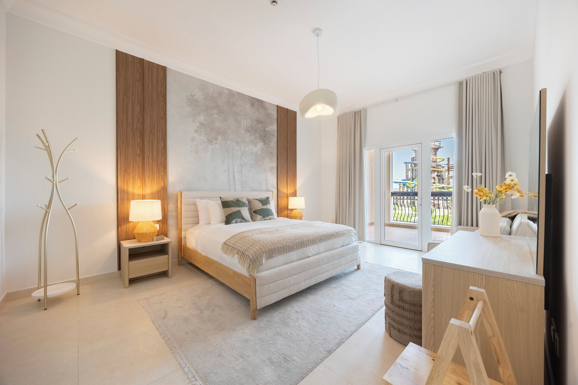 Habitación de hotel moderna con cama, lámparas de noche, un amplio ventanal y vistas a un área exterior.
