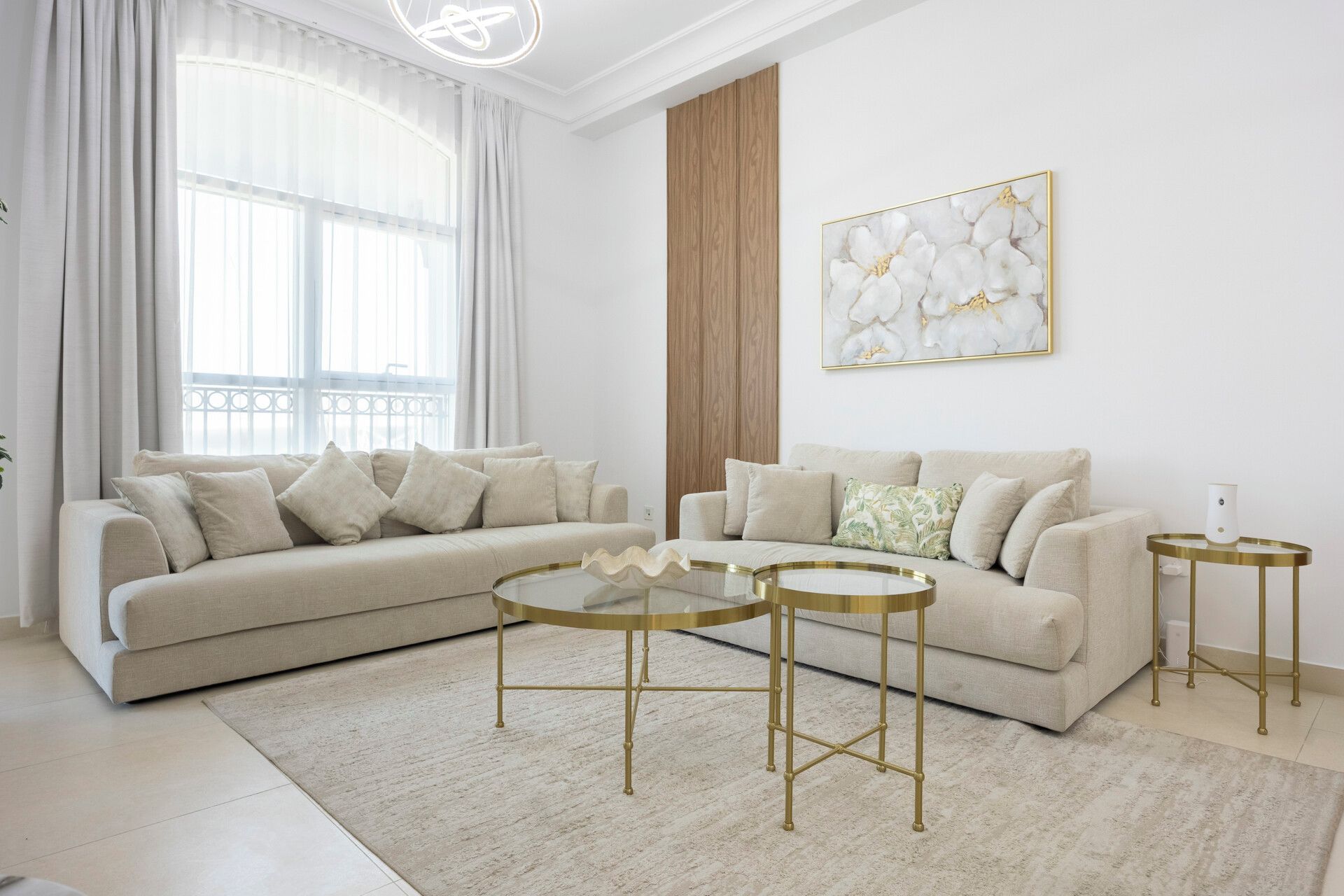 Een moderne woonkamer met een modulaire bank, twee bijzettafels en een decoratief kunstwerk aan de muur.