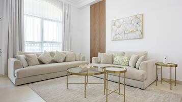 Een moderne woonkamer met een modulaire bank, twee bijzettafels en een decoratief kunstwerk aan de muur.