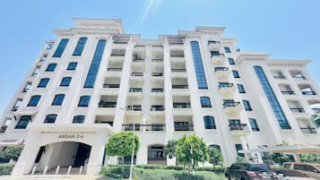 A multi-story hotel with a central entrance, balconies on each floor, and a clear sky above.