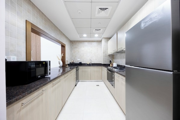 Una cocina moderna con electrodomésticos de acero inoxidable, armarios de madera clara y un salpicadero de azulejos.