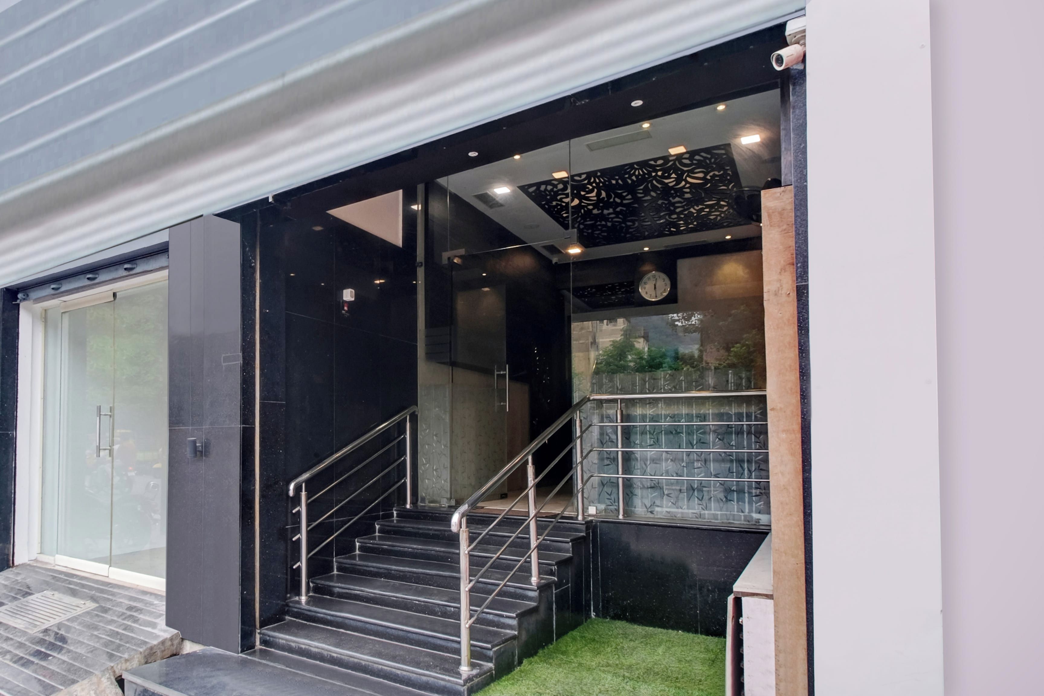 Una escalera moderna con barandas de metal que conduce a un acceso por puerta de vidrio.