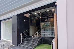 Una escalera moderna con barandas de metal que conduce a un acceso por puerta de vidrio.