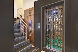 Una escalera con barandales de metal que conduce a una puerta de madera con una reja de seguridad.