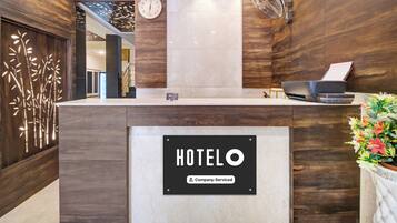 Una recepción de hotel con un reloj, un letrero de la empresa y un ventilador.