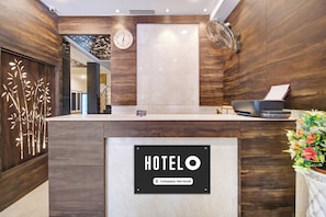 Una recepción de hotel con un reloj, un letrero de la empresa y un ventilador.