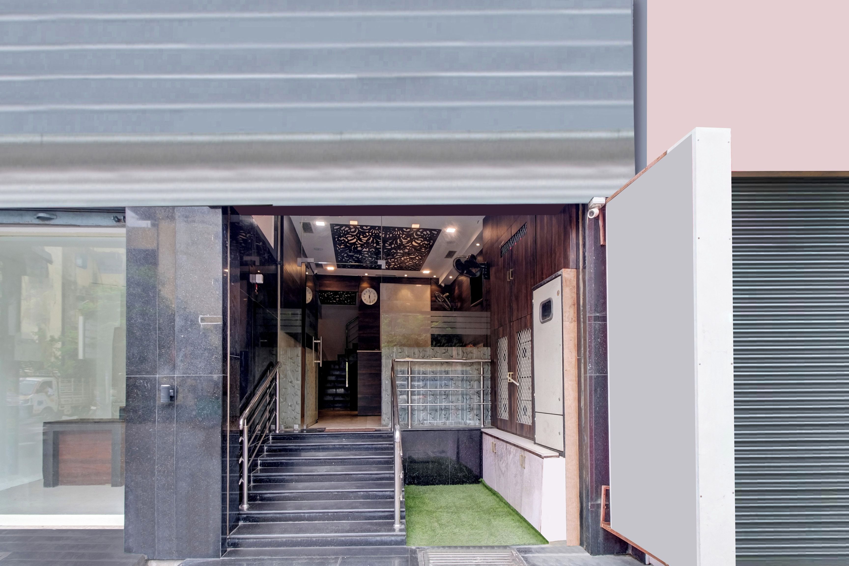 Entrada moderna de un edificio con fachada de vidrio, una escalera que conduce a un nivel superior y un techo decorativo.
