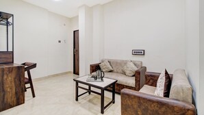 A living room with a sofa, a coffee table, a TV, and a ceiling fan. - Hotel O Vijayawada Near Railway Station (Vijayawada)