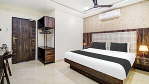 A hotel room with a bed, a wardrobe, a desk, and a ceiling fan. - Hotel O Vijayawada Near Railway Station (Vijayawada)