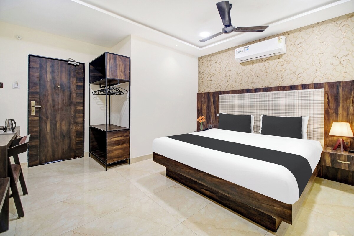 Quarto de hotel com cama, guarda-roupa, escrivaninha e ventoinha no teto.