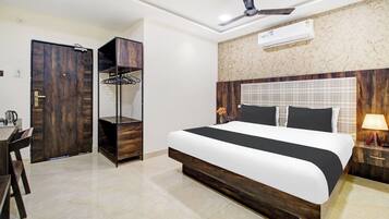 Una habitación de hotel con una cama, un armario, un escritorio y un ventilador de techo.