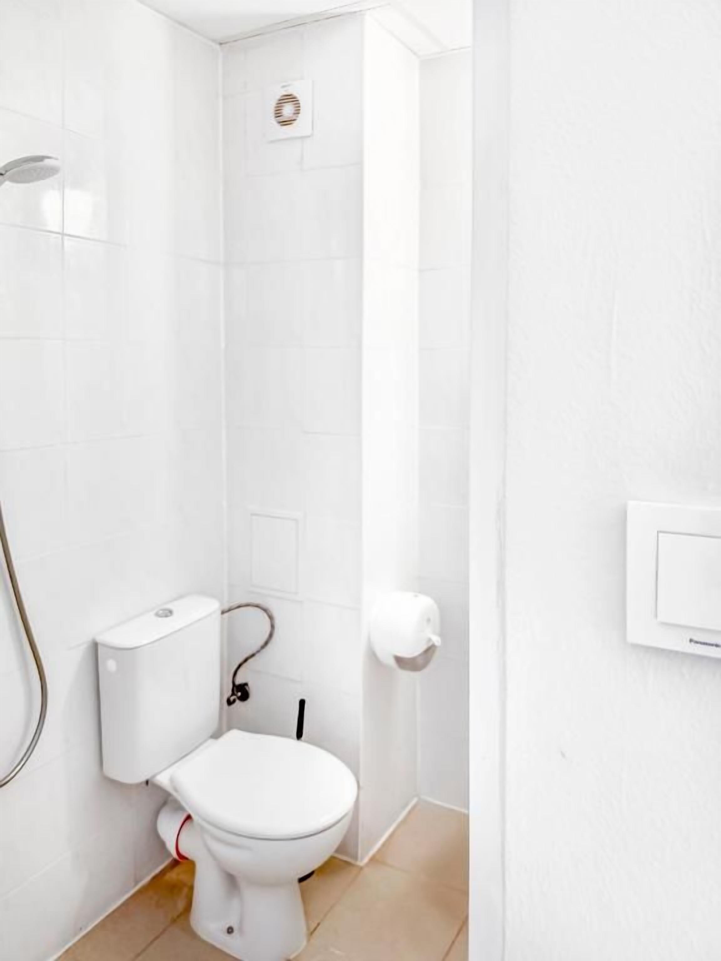 Ein Badezimmer mit Toilette, Dusche und Handtrockner.