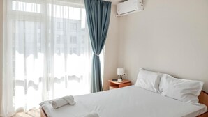 Ein Hotelzimmer mit Bett, Nachttisch, Klimaanlage und Blick aus dem Fenster.