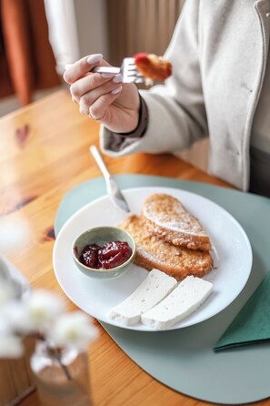 A plate with a slice of cake, a small bowl of jam, and two pieces of cheese on a table.