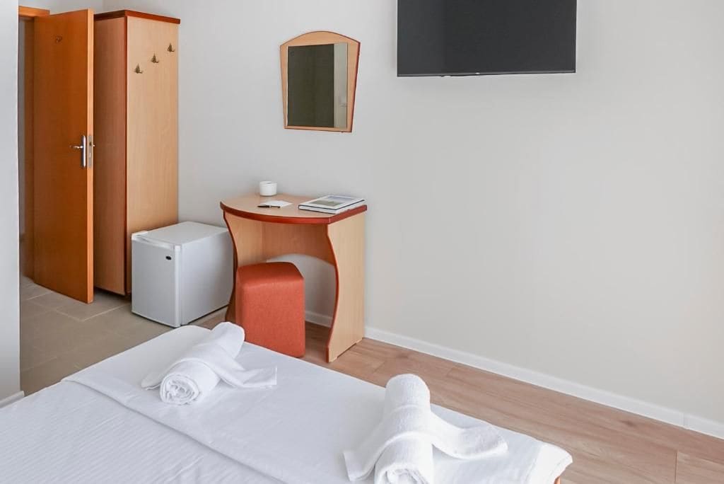Una habitación de hotel con cama, escritorio, refrigerador pequeño y armario.