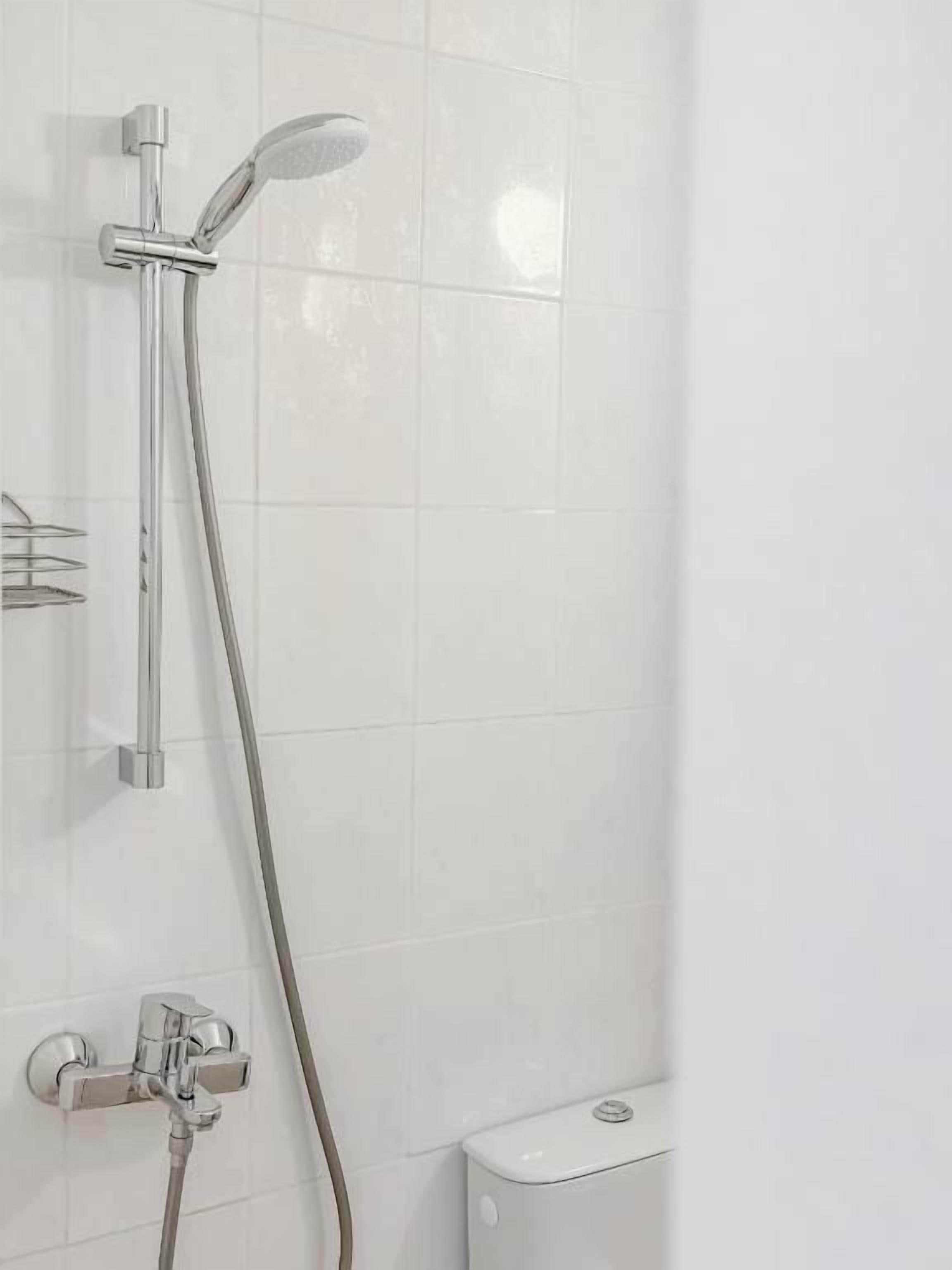 Een douche met een handdouche en een wandmengkraan.