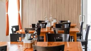 A restaurant with multiple tables and chairs, a wooden wall, and an air conditioning unit.