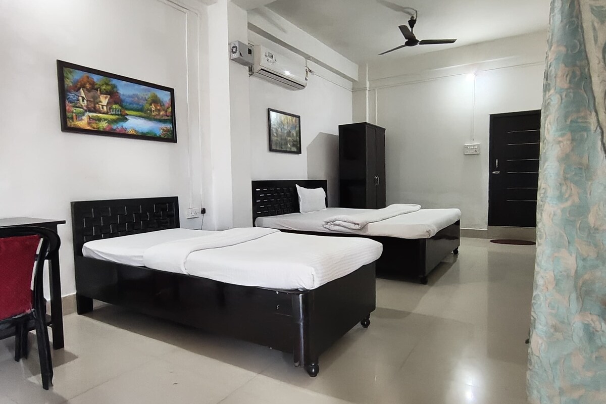 A bedroom with two beds, a desk, and a wardrobe.