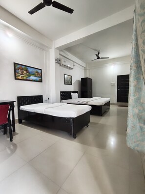 A bedroom with two beds, a desk, and a wardrobe.