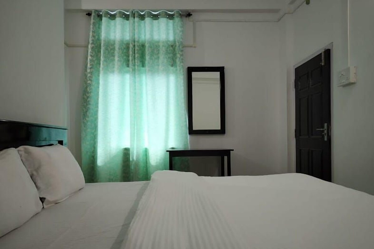 A bedroom with a bed, a nightstand, a mirror, and a door.