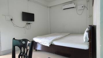 A room with a bed, a chair, a ceiling fan, a TV, and an air conditioning unit.