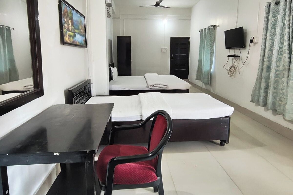 A hotel room with a bed, a desk, a chair, a television, and a ceiling fan.