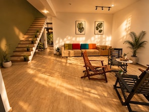 Un saló modern amb una escala de fusta, un sofà amb coixins de colors i una zona de menjador amb taula i cadires.