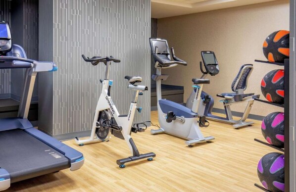Un gimnasio con bicicletas estáticas, cintas de correr y pelotas de ejercicio.