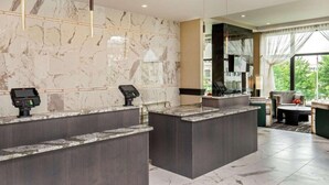 A hotel reception area with marble walls, two reception counters, and a seating area with a view. - Steps From Downtown + On-Site Dining, King Bed (Youngstown)