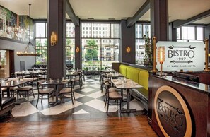A restaurant interior with a checkered floor, wooden tables, and a bar area. - Prime Downtown 2 Queen Room | On-Site Dining (Youngstown)