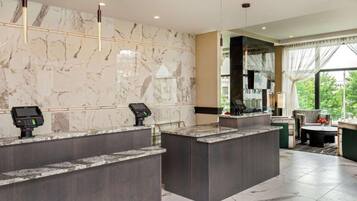 A hotel reception area with marble walls, two reception counters, and a seating area with a view.