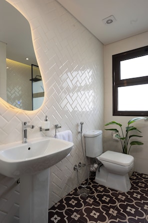 A bathroom with a white herringbone tile wall, a white sink, a toilet, and a window with a black frame. - Delightful stay at Degla by Spacey #39 (Cairo)