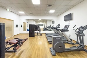Et fitnesscenter med løbebånd, crosstrainere og styrkeudstyr.