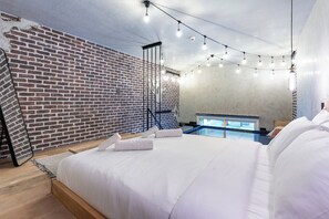 Ein modernes Schlafzimmer mit Ziegelwand, einem Bett mit weißer Bettwäsche, einem kleinen Billardtisch und Lichterketten.