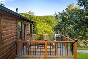 Eine Holzhütte mit einer Terrasse und einem Grill.