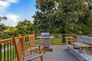 Un patio in legno con una griglia per barbecue e un'area salotto.