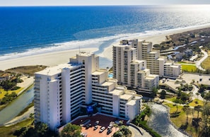 Un complex hoteler a la costa amb diversos edificis alts, una platja i un riu que travessa la propietat.