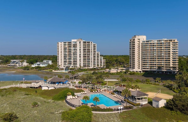Un complex turístic amb piscina, diversos edificis alts i una zona de platja.