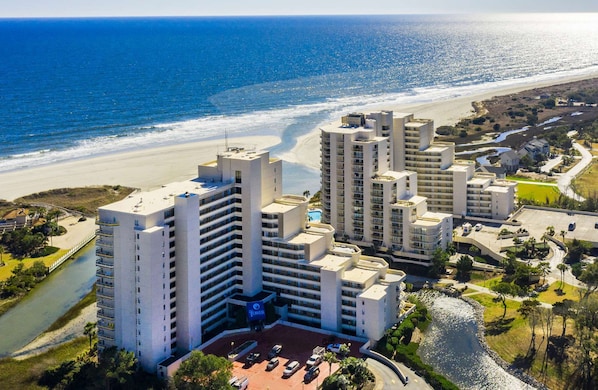Un complex hoteler a la costa amb diversos edificis alts, una platja i un riu que travessa la propietat.