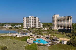 Un complex turístic amb piscina, diversos edificis alts i una zona de platja.