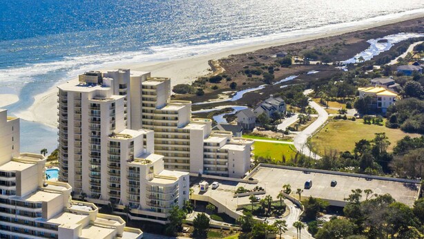 Ein Küstenhotel mit mehreren Hochhäusern, einem Strand und einem Parkplatz.