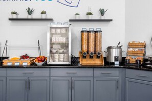 A kitchen with a refrigerator, a coffee machine, and various food items on the counter. - Near Disney World Resort + Free Breakfast. Shuttle (Kissimmee)