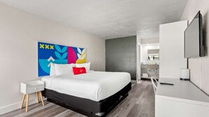 Une chambre d’hôtel moderne, équipée d’un lit, d’une table de chevet et d’un grand miroir.