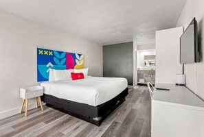 Ein modernes Hotelzimmer mit Bett, Nachttisch und einem großen Spiegel.